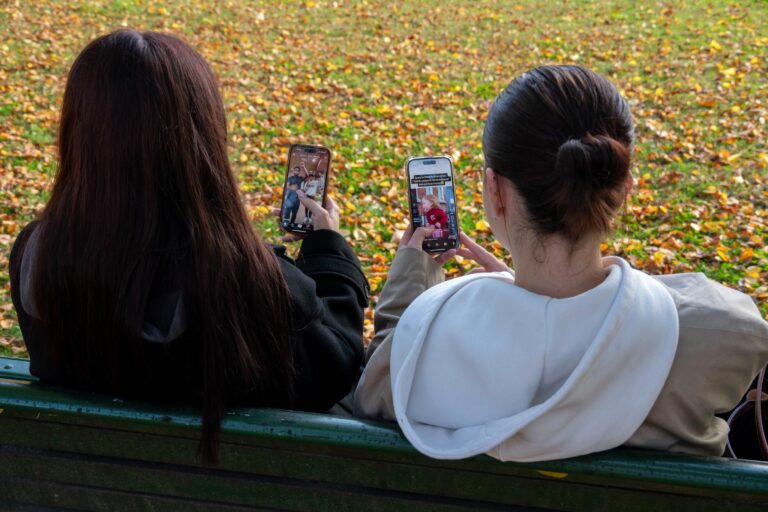 Deux adolescentes sur un banc qui regardent les deux leur propre téléphone en train de "doomscroll".